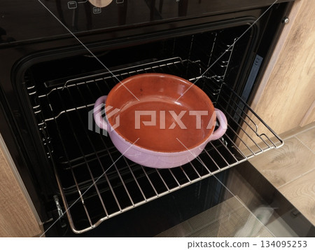 Empty ceramic pan with two handle, pot baking dish for roasting food in oven on rack. Traditional national cookware, Europe. Healthy eating at home. Mock up for design.  134095253