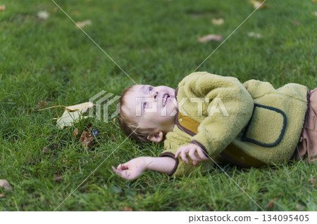 Toddler Child Lying and Smiling on Green Grass in Park Toddler Child Lying and Smiling on Green Grass in Park 134095405