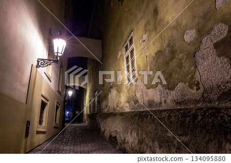 Nighttime cobblestone alley is being shown in flat design, with metal lanterns and archways 134095880
