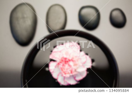 Flower floating in bowl by pebbles Flower floating in bowl by pebbles 134095884
