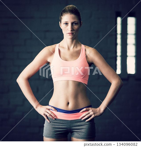 Woman with hands on hip standing at gym Woman with hands on hip standing at gym 134096082