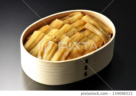 一個盛有煮熟康吉鰻的便當盒,在黑色背景下拍攝的照片。 一個盛有煮熟康吉鰻的便當盒,在黑色背景下拍攝的照片。 134096521
