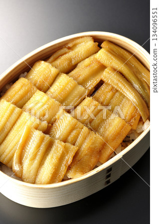 A bento box of boiled conger eel in a bento box photographed against a black background 134096551