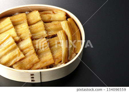 A bento box of boiled conger eel in a bento box photographed against a black background 134096559