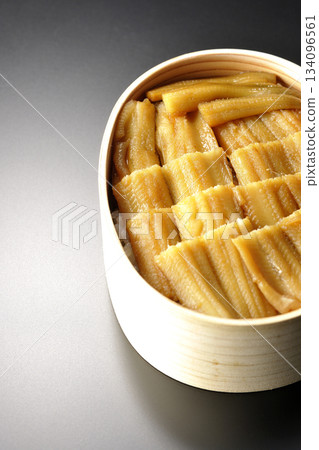 一個盛有煮熟康吉鰻的便當盒，在黑色背景下拍攝的照片。 134096561