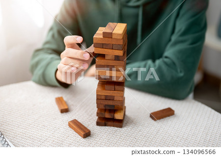 Close up of a man's hand taking out a piece of wooden blocks in tower building game as playing alone 134096566