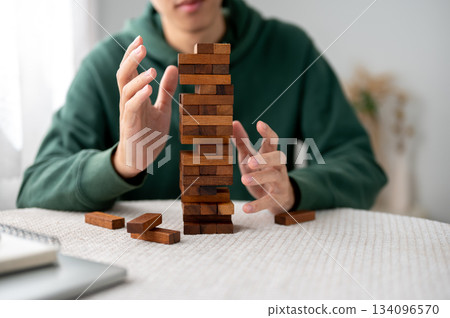 Close up of man looking with hands hovering aside wooden blocks of tower building game playing alone 134096570