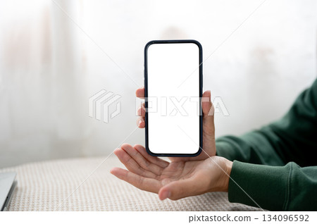 Close up man hand holding and showing or presenting a white screen phone at table in cafe or library 134096592