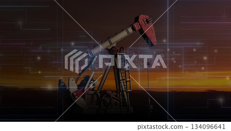 Operating red and grey oil pumpjack on remote plain at sunset, with digital circuit overlay 134096641