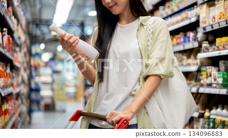 Chiang mai, Thailand - September 16th, 2025: Woman choosing product to shopping cart in supermarket Chiang mai, Thailand - September 16th, 2025: Woman choosing product to shopping cart in supermarket 134096883
