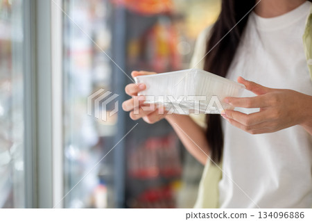 Close up woman customer holding or buying a fresh food cooking ingredient from fridge in supermarket 134096886
