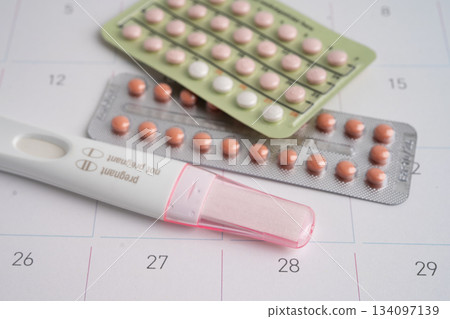 Pregnancy test and condom for female on calendar, ovulation day. 134097139