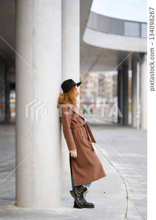 Woman leaning against a column in a city area during the daytime 134098267