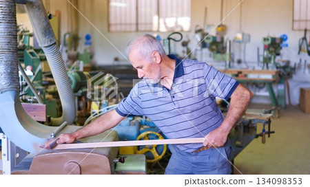 Senior carpenter sanding wood plank in workshop Senior carpenter sanding wood plank in workshop 134098353