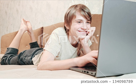 Caucasian teenage boy using laptop, depicting focus and modern indoor lifestyle. Teen focused laptop Caucasian teenage boy using laptop, depicting focus and modern indoor lifestyle. Teen focused laptop 134098789