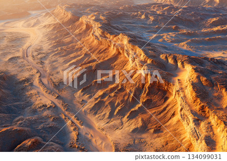 The scene shows rugged mountains and dust paths under the warm light of sunset with a clear sky above 134099031