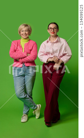 Confident senior women posing together on green backdrop 134099125