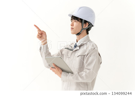 A young man in work clothes holding a tablet A young man in work clothes holding a tablet 134099244