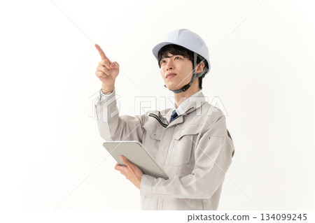 A young man in work clothes holding a tablet 134099245
