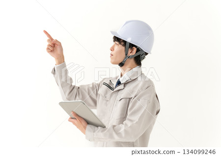 A young man in work clothes holding a tablet A young man in work clothes holding a tablet 134099246