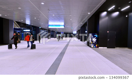 Warsaw, Poland. 28 November 2025. Commuters going through the underground passage hall at Warszawa Zachodnia train station. Ceiling mounted large artificial illumination. 134099367