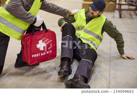 Warehouse worker receives first aid after injury accident, safety response 134099663