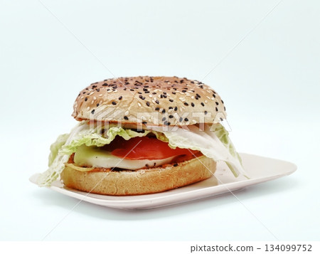 Bright lighting highlights layered greens on seeded bagel Bright lighting highlights layered greens on seeded bagel 134099752