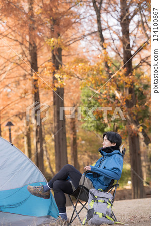 一位獨自露營的男士在秋日營地的椅子上放鬆身心,享受戶外時光,欣賞美景。 一位獨自露營的男士在秋日營地的椅子上放鬆身心,享受戶外時光,欣賞美景。 134100867