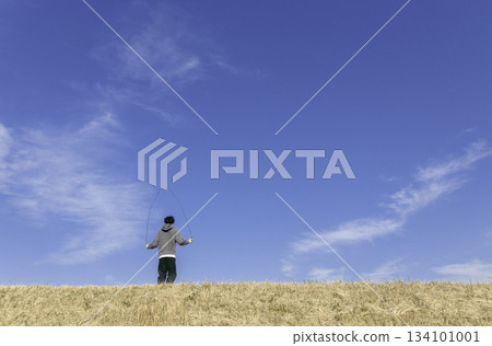 一個男孩在藍天和冬日河岸下跳繩 134101001