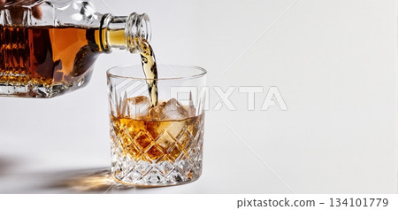 Smooth whiskey pour into an ice-filled glass with a clean white background 134101779