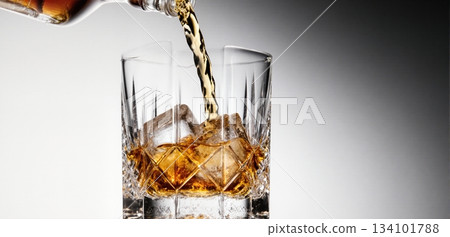 Smooth whiskey pour into an ice-filled glass with a clean white background 134101788