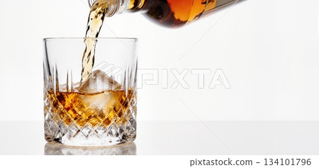 Smooth whiskey pour into an ice-filled glass with a clean white background 134101796