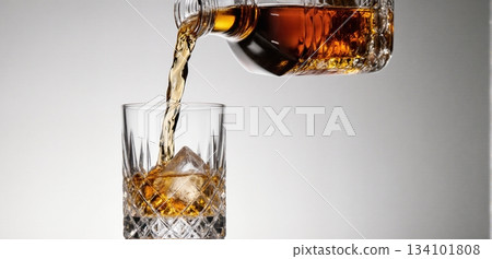 Smooth whiskey pour into an ice-filled glass with a clean white background 134101808