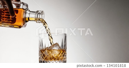 Smooth whiskey pour into an ice-filled glass with a clean white background 134101818