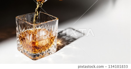 Smooth whiskey pour into an ice-filled glass with a clean white background 134101833