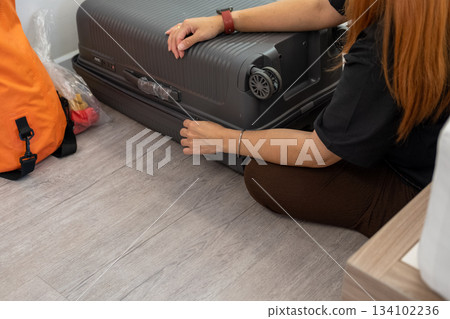 Asian woman arranging clothing neatly in luggage, capturing a relaxed vacation planning moment Asian woman arranging clothing neatly in luggage, capturing a relaxed vacation planning moment 134102236