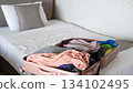 Traveler packing an open suitcase on the bed, organizing essentials for an upcoming journey 134102495