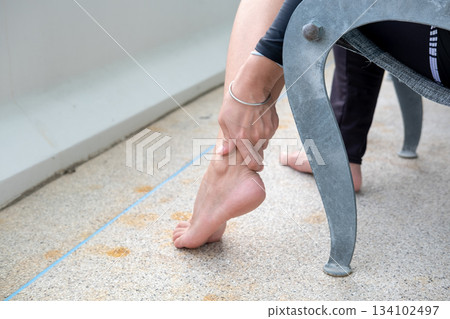 Young Asian woman massaging her ankle on balcony chair, calming wellness moment with fresh air 134102497