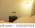 Travel-ready large suitcase placed by the bed in a neat room, showing journey and accommodation 134102504
