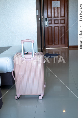 Suitcase standing by the bedside in modern hotel room, showcasing vacation arrival atmosphere Suitcase standing by the bedside in modern hotel room, showcasing vacation arrival atmosphere 134102525