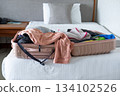 Open suitcase on hotel bed with travel items being prepared, capturing vacation planning moment 134102526