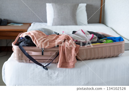 Open suitcase on hotel bed with travel items being prepared, capturing vacation planning moment 134102526