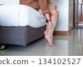 Young Asian woman massaging her ankle on the bed, soothing pain relief and peaceful relaxation 134102527