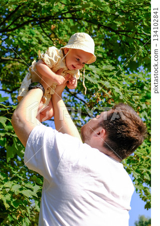 Father Lifting Baby Under Tree 134102841