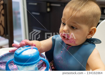 Baby Enjoying a Messy Meal in High Chair Baby Enjoying a Messy Meal in High Chair 134102864
