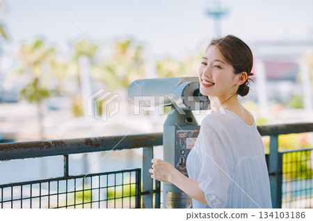 年輕女子透過望遠鏡欣賞旅遊景點的景色 年輕女子透過望遠鏡欣賞旅遊景點的景色 134103186