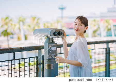 Young woman enjoying the view of a tourist spot through a telescope Young woman enjoying the view of a tourist spot through a telescope 134103261