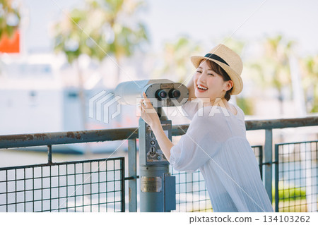 Young woman enjoying the view of a tourist spot through a telescope 134103262