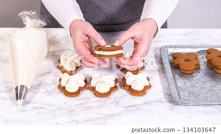 Gingerbread cookies await their second halves on a marble surface, each meticulously piped with buttercream to craft delightful sandwich treats. The precision of the piping adds a festive touch. Gingerbread cookies await their second halves on a marble surface, each meticulously piped with buttercream to craft delightful sandwich treats. The precision of the piping adds a festive touch. 134103647
