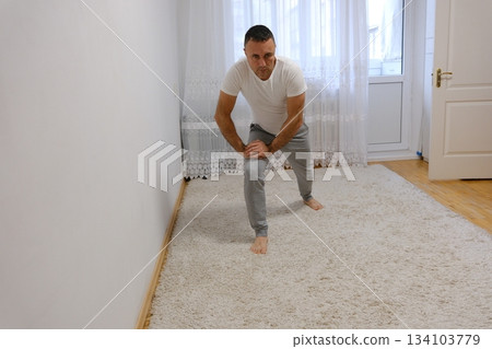 forward lunges exercise Strong Athletic Fit Man in T-shirt and Shorts is Doing Forward Lunge Exercises at Home in His Spacious and Bright Apartment with Minimalistic Interior. 134103779